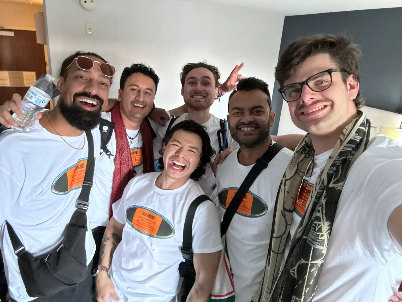 The creators of Lightning Alert Tees smiling in a group selfie wearing the white tees with the chrome oval front print